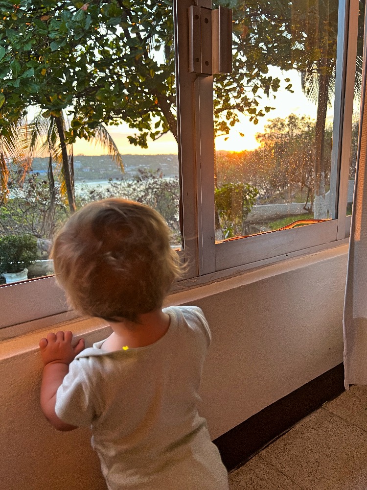 Lucía viendo el amanecer desde la ventana